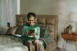© Westend61 - Smiling woman using tablet PC sitting on bed at home