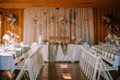 Valmiera, Latvia - Augist 13, 2023 - Rustic wedding venue with tables, chairs, and fairy lights against wooden interior.