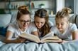 Three girls are reading a book together on a bed