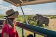 A Caucasian girl in a hat looks at animals in the savannah. The concept of travel and adventure in the wild. Young woman discover african nature by car with an open roof. Tanzania safari