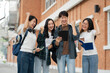 Happy group of college students use laptop feel excited overjoyed triumph with good news over smartphone or Tablet.