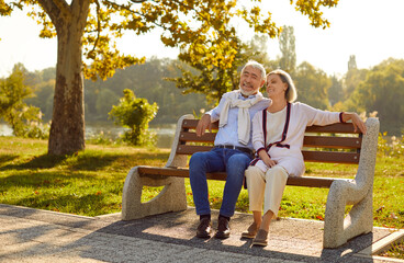 seniors rest outdoors. beautiful stylish elderly couple in love is sitting on bench in city park on 