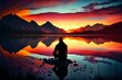 person sitting on rock looking at mountains and lake under sunset