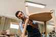 © chokniti - Diligently skilled man work with wood in carpenter's shop, using tools and equipment to transform timber planks into bespoke wooden pieces, craftsmen workshop with natural material, furniture industry