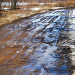 A muddy spring country road with puddles and melting snow