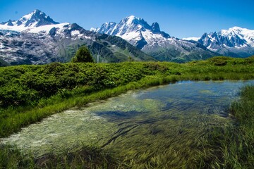 Poster - Landscape of a lake with grass fields in charamillon gondola snowy alps in Haute Savoie, France