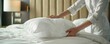 Close-up of housekeeper placing pillow on bed with precision and care
