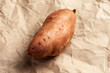 Unpeeled sweet potato on paper. Fresh batata root