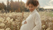 Pregnant woman in knitted sweater holding belly