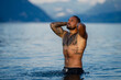 Sexy muscular man standing in summer water. Summer Travel vacation holiday. Relax man, freedom, calm and carefree on summer nature concept. Muscular man in Alps lake. Man freedom lifestyle in nature.