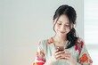 © PhotoPhantom - Beautiful Japanese woman with casual clothes seen tapping on phone with copy space to the right