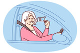 Fototapeta Kwiaty - Happy elderly woman demonstrates driver license sitting behind wheel of car and rejoices at opportunity to go on road trip. Positive grey-haired old lady got driver ID after retirement