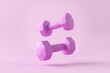 Pink dumbbells levitating on pink background with copy space.