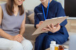 healthcare worker filling in a form with a senior woman during a home health visit