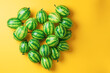 A collection of striped watermelon berries form a fresh, vibrant pattern on a vivid yellow background, offering a visually stimulating contrast and summery feel
