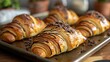 closeup of baked croissants with chocolate on baking sheet, homemade baking concept
