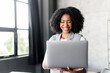 A charismatic African-American businesswoman holds her laptop, her face alight with joy, possibly celebrating an accomplished goal or milestone. A joy and achievement in the professional sphere.