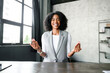 An African-American businesswoman smiles joyfully as she gestures during a video conference, her charismatic communication style enhancing her message in a modern, minimalist office setting.