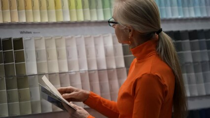 Wall Mural - Closeup of mature woman looking at paint chips in a hardware store. Concept of shopping experience for home improvement.