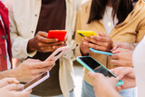Fototapeta Londyn - Closeup view of young group of people hands using mobile phone outdoors. Millennial people connected online browsing internet on smartphone device.