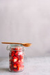 FRische gewürfelte Erdbeeren in einem Einmachglas mit einem Holz Löffel auf einem grauen Tisch. 