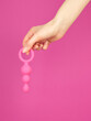 Woman's hand holding adult sex toy over pink background