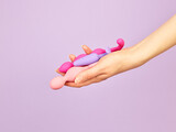 Fototapeta  - Woman's hand holding adult sex toys over violet background