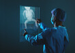 Doctor looking at total hip replacement X-ray film with blurred hospital background.