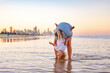 © Austockphoto - Mother holding toddler son upside down on Gold Coast beach