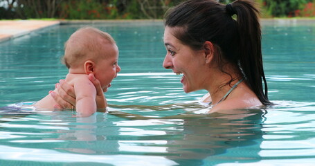 Wall Mural - Mother holding baby son inside swimming pool water interaction