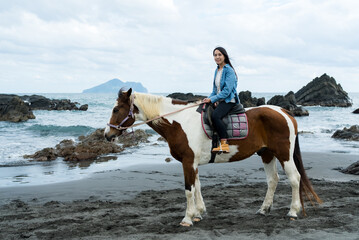 Wall Mural - Tourist woman ride a horse beside the sea beach