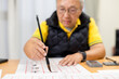 © leungchopan - Asian old man practice Chinese characters with calligraphy at home
