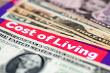 Fototapeta Londyn - A macro close up of US dollar bills and the words cost of living. A living cost and inflation concept.