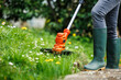 Grass trimmer. Woman is cutting grass in garden. Lawn care in spring