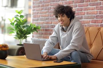 Sticker - Student in a cafe sitting on a sofa and using a laptop