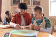 © Mediaphotos - Portrait of smiling boy with disability enjoying art class in studio with mentor assisting