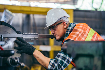 Wall Mural - Male engineer metalworker industrial experienced operator technician worker in safety hard helmet working on lathe machine, professional man in industry technology manufacturing factory workshop