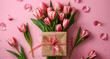 Bouquet of pink tulips and gift box on pink background, perfect for celebrations and romantic gestures.