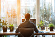 © MariiaDemchenko - Man working on computer in cozy home office with natural light. Back view. Remote work from home, telecommuting, freelance