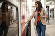 Business woman entering a train on train station, using mobile phone, looking directly on train