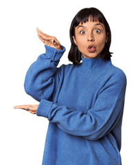 Poster - Young Hispanic woman with short black hair in studio shocked and amazed holding a copy space between hands.