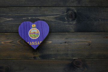 wooden heart with national flag of kansas state on the wooden background.