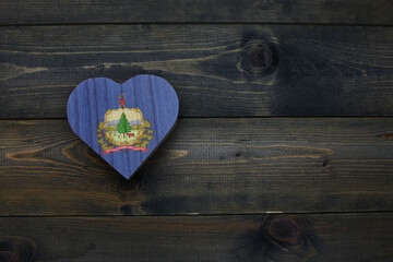 Wall Mural - wooden heart with national flag of vermont state on the wooden background.