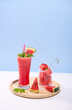 fresh watermelon juice or smoothie in glasses with watermelon pieces on studio background. Refreshing summer drink