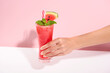 hand holding fresh watermelon juice or smoothie in glasses with watermelon pieces on studio background. Refreshing summer drink