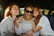 Three friends sharing a moment of joy during a car trip on a bright sunny day, evoking feelings of friendship and adventure.