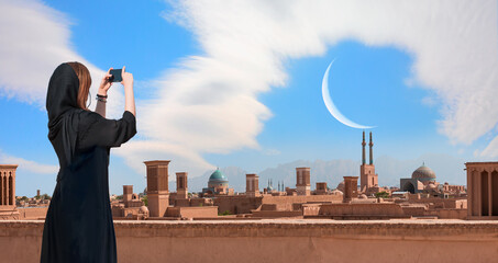 Wall Mural - Beautiful Iranian girl wearing abaya with taking selfie - Historic City of Yazd with famous wind towers - YAZD, IRAN