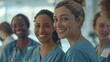 A group of nurses standing close to each other and smiling at the camera. They are all women and wear blue robes.
