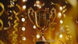 Shiny trophy cup surrounded by gold ribbons and glitter on dark background.