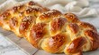 Golden braided challah bread with shiny glaze and sesame seeds displayed on a kitchen table